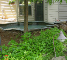 Outdoor ground light fixture next to green plants.