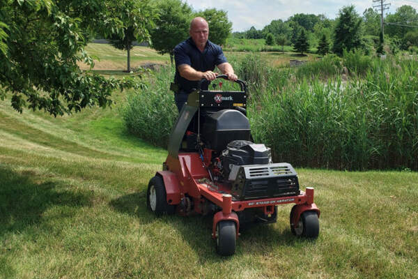 Skilled worker operating a lawn mower, diligently cutting grass to maintain the pristine condition of the lawn.