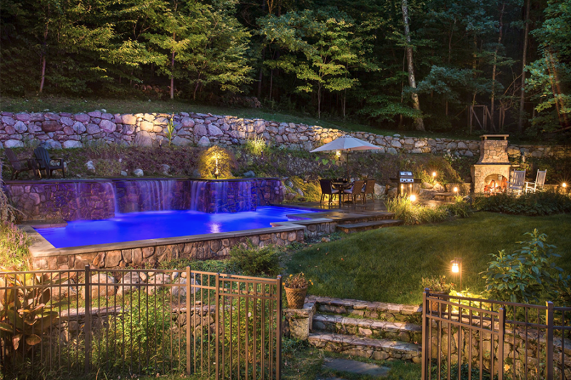 Vibrant pool and landscape illuminated by captivating lighting concept image for the benefits of landscape lighting