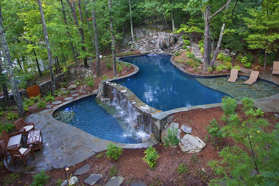 Captivating outdoor infinity pool gracefully cascading to a lower pool, embraced by the beauty of nature's greenery, offering a serene and harmonious escape by expert outdoor living space contractor and pool renovation specialist in Briarcliff Manor, New York.