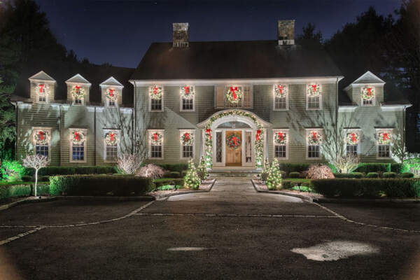 Charming house adorned with festive Christmas decorations, featuring twinkling lights on trees and meticulously maintained hedges, radiating warmth and holiday cheer in Briarcliff Manor, New York