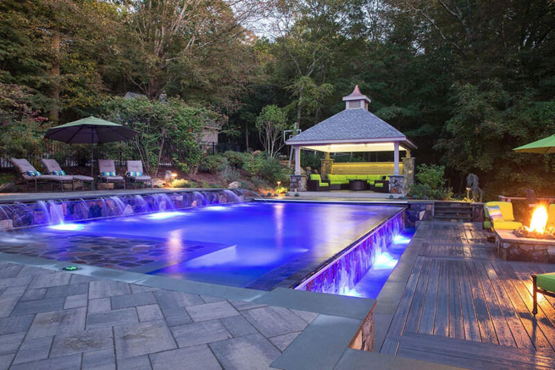 An opulent outdoor pool nestled in a lush oasis, crafted by our premier outdoor living space contractor in Katonah, NY