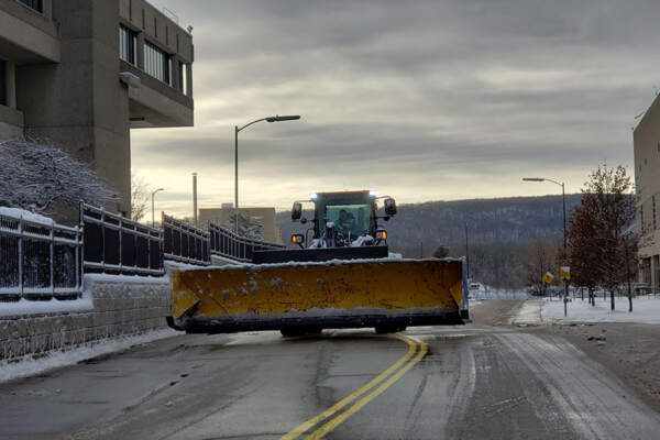 Proficient operator clearing snow with a large snow plow to maintain safe outdoor areas during winter.