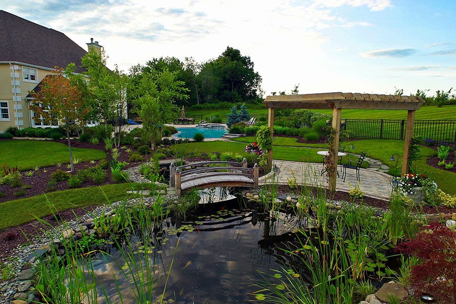 Scenic backyard with a pond, charming bridge, and pool, creating a tranquil oasis in a well-designed outdoor space