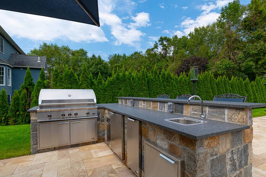 Stone outdoor kitchen with stainless steel appliances, showcasing expert outdoor design and functional luxury