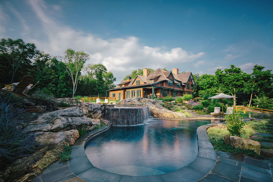 Stunning luxury home with a waterfall pool, showcasing top luxury outdoor design tips for creating serene outdoor retreats