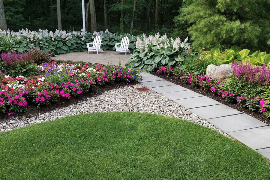 Walkway leading to Adirondack chairs surrounded by vibrant native plants emphasizing sustainable landscape design